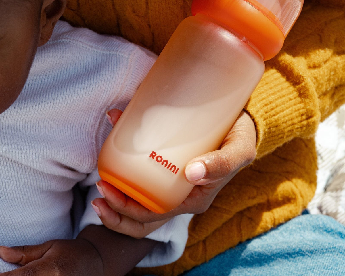 A parent holding The Wrapped Glass Bottle against a mustard sweater