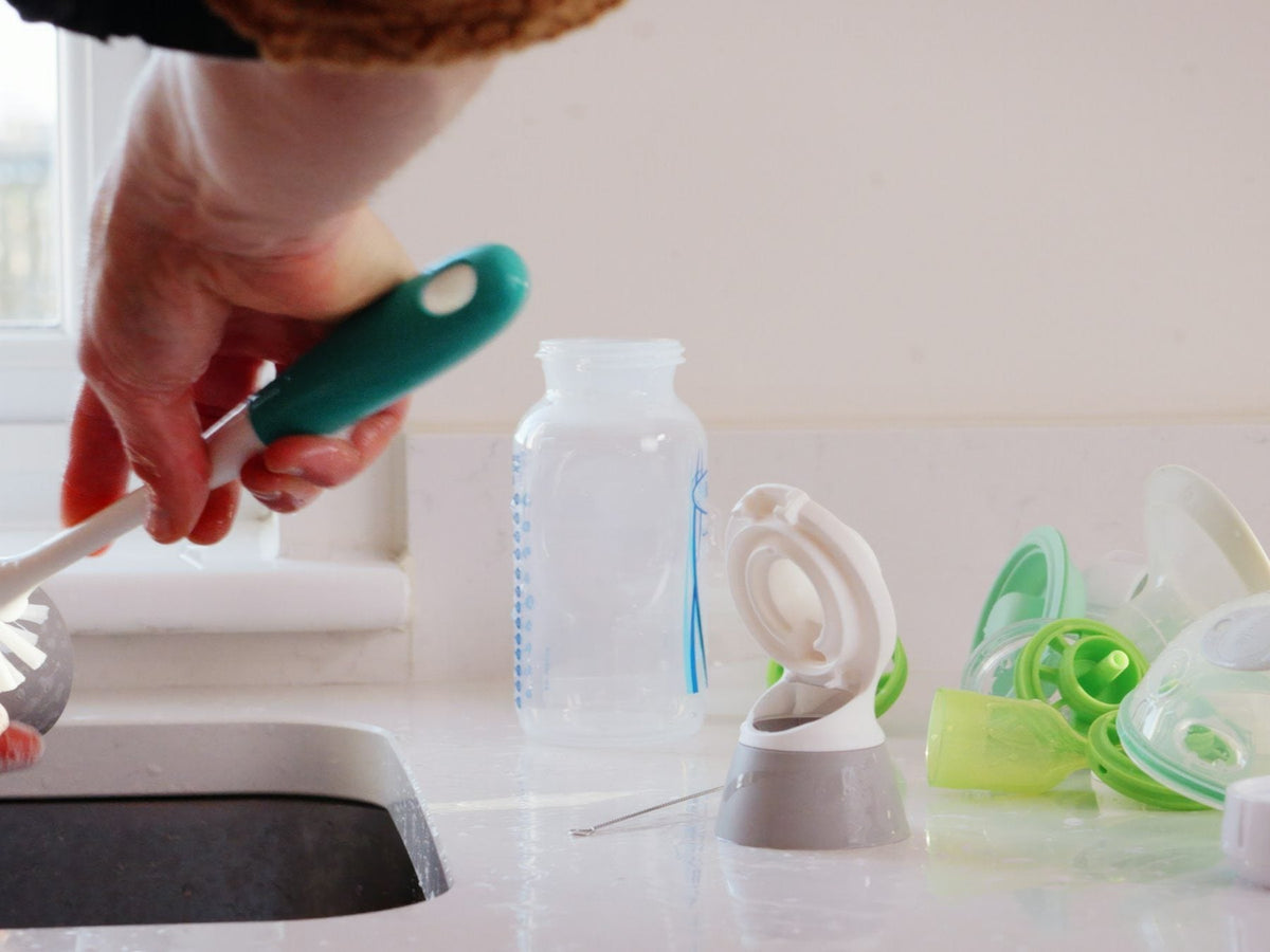 Cleaning bottle parts with a brush at the sink